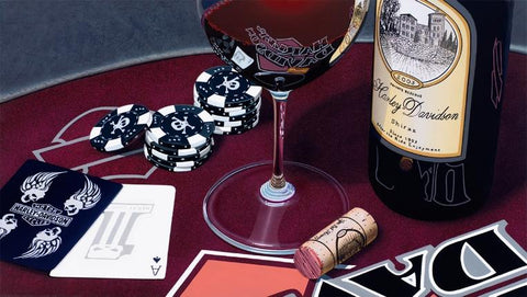 Painted image by Scott Jacobds with a Harley Davidson wine bottle sitting next to a wine glass with poker chips and playing cards on a maroon table.